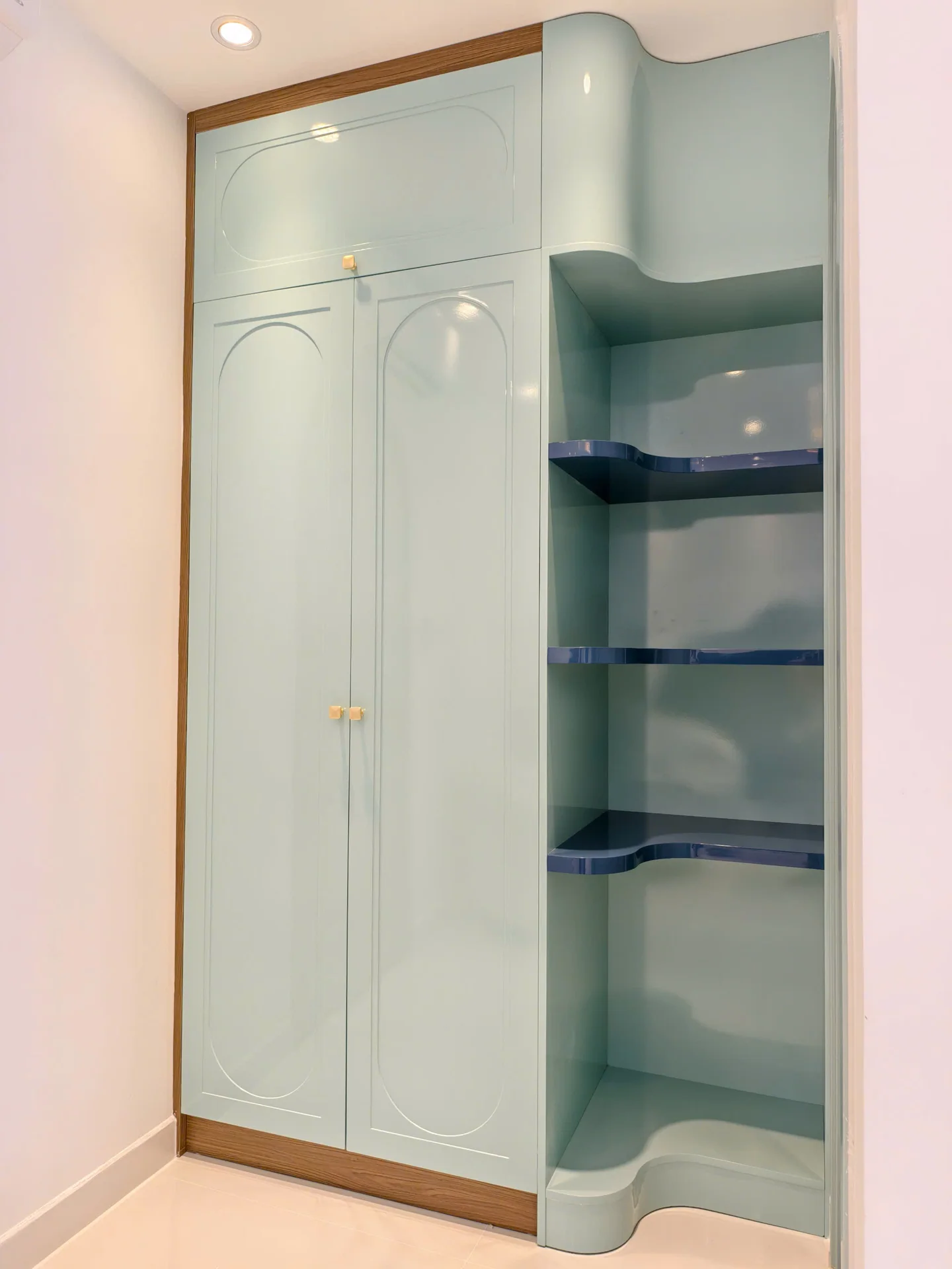 Ảnh thực tế tủ áo cao màu xanh nhạt cánh kín, bên cạnh là kệ mở bo cong, công trình D.HOUSE tại NovaWorld Phan Thiết